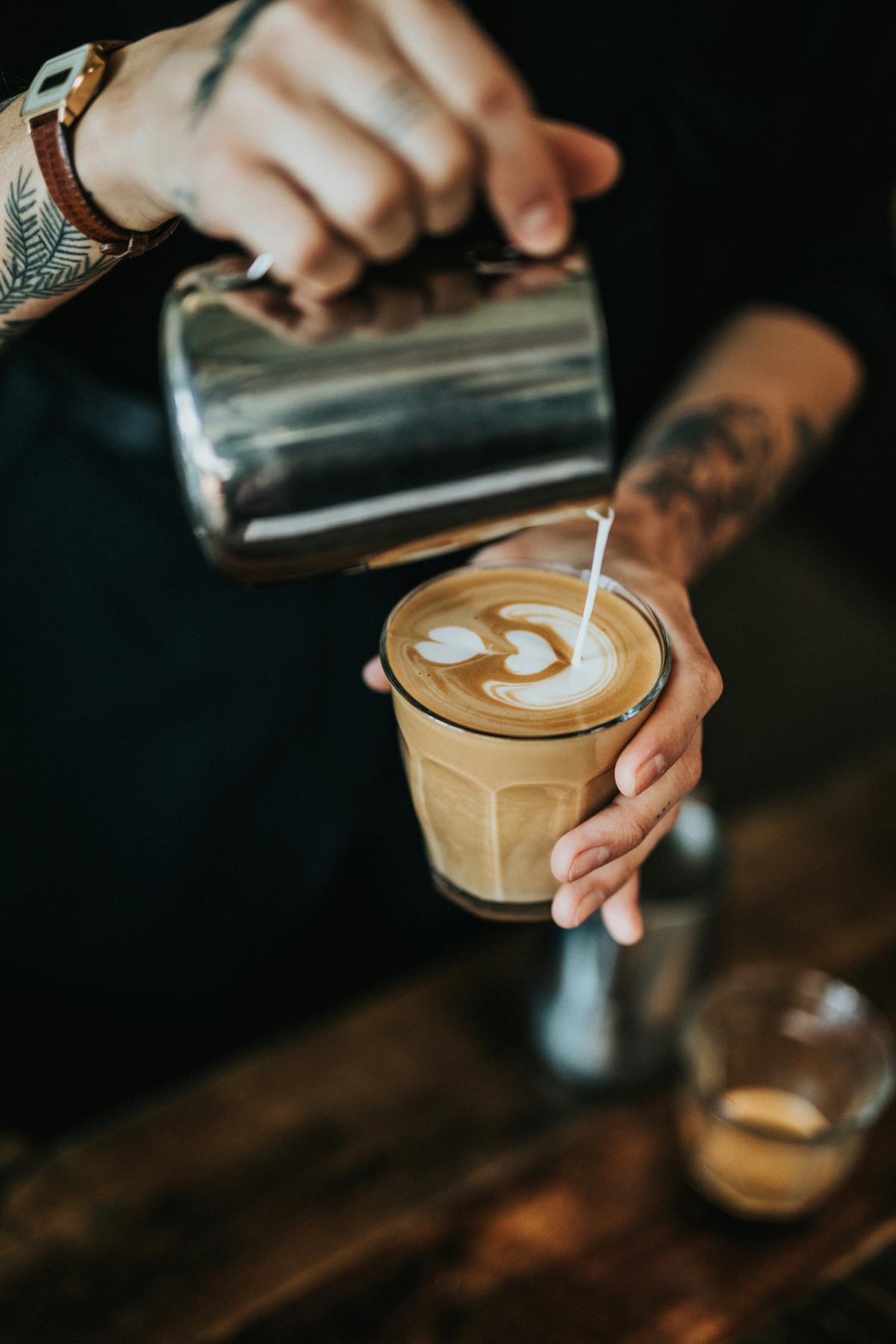 Milk poured into a latte in a glass, with a heart in the foam